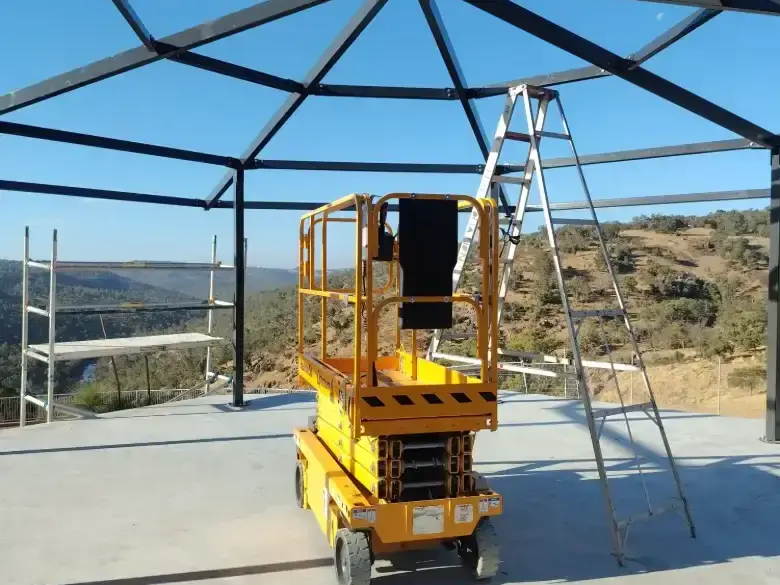 Electric scissor lift working inside an enclosed structure with the platform raised